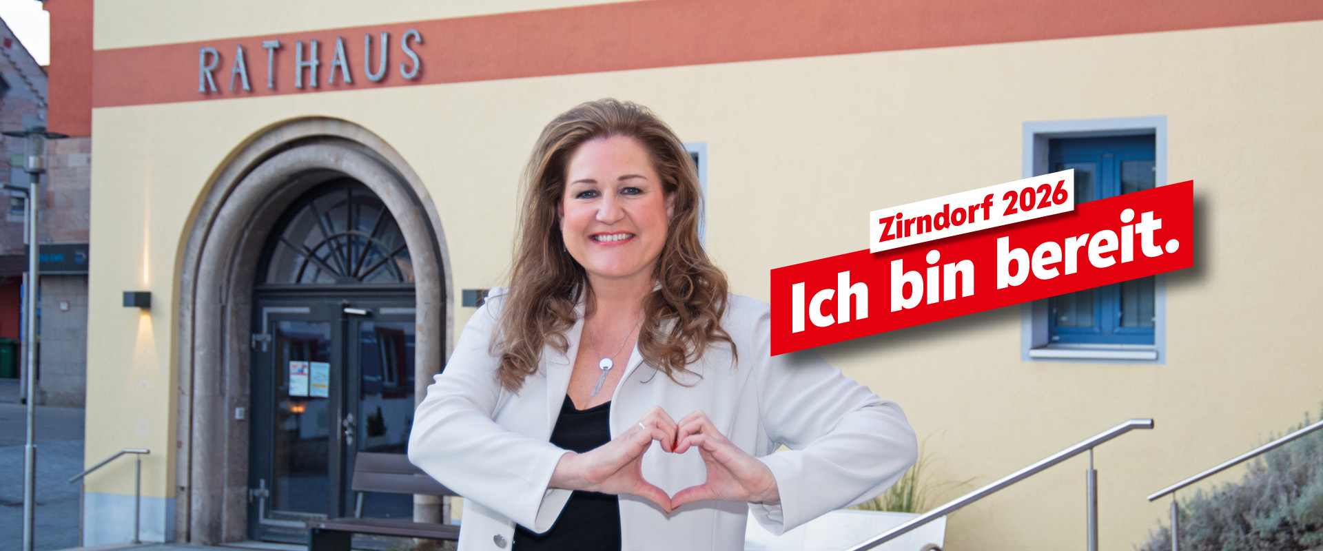 Sandra Hauber, Bürgermeisterkandidatin für Zirndorf, lächelt und zeigt mit ihren Händen ein Herz
